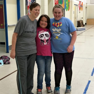 Two smiling Girls on the Run coaches holding participant